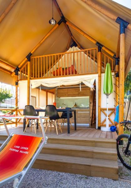 Glamping-Zelt mit Terrasse, Stühlen und Fahrrad im Campingplatz.