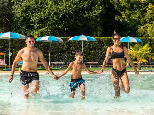 Happy family running in the pool on a sunny day.