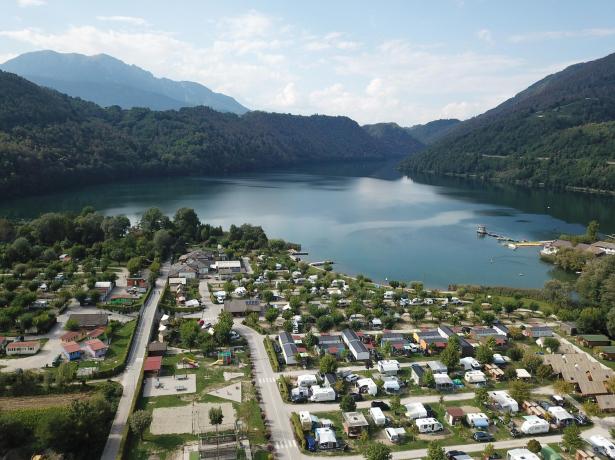 Luftaufnahme eines Campingplatzes an einem von Bergen umgebenen See.