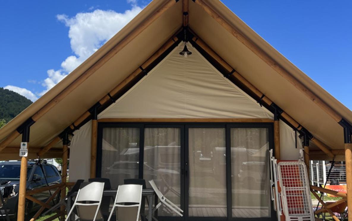 Moderne glamping-tent met houten veranda en stoelen.