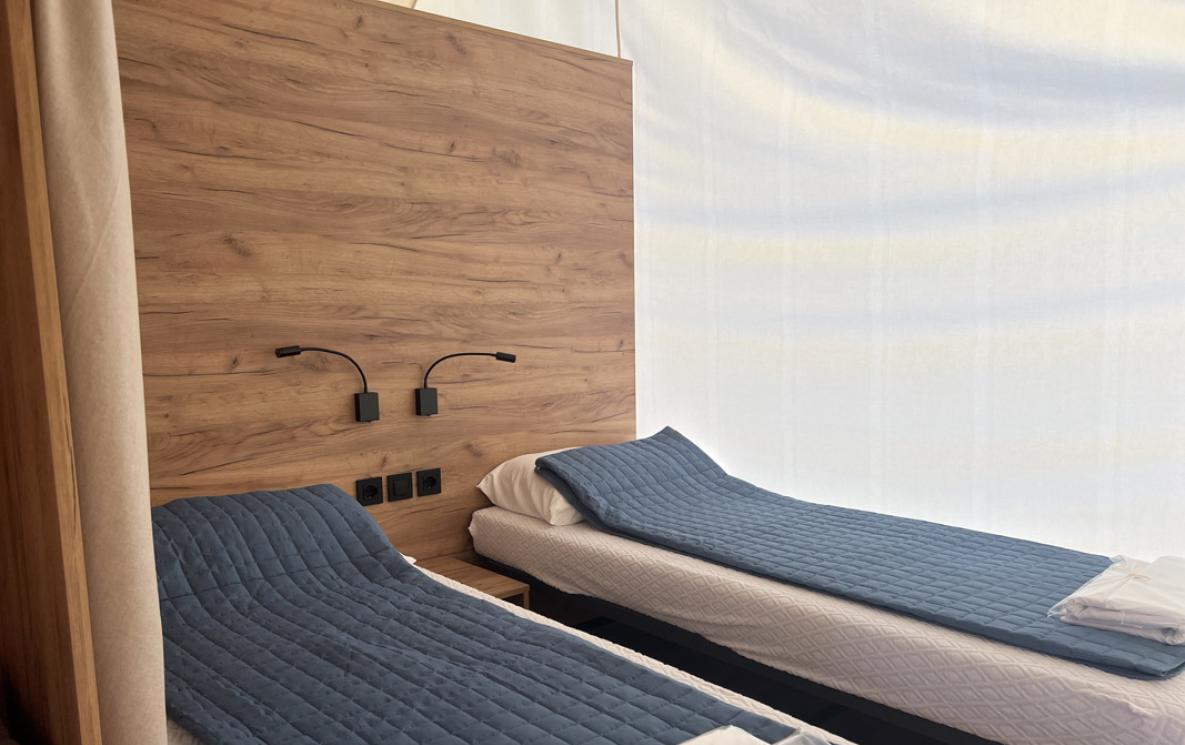 Moderne kamer met twee eenpersoonsbedden en blauwe dekens.