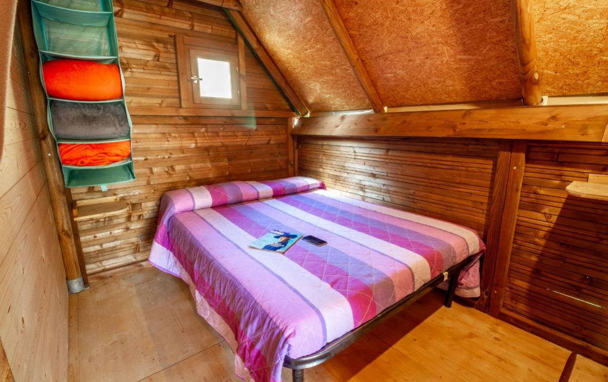 Camera da letto in legno con letto matrimoniale e finestra.