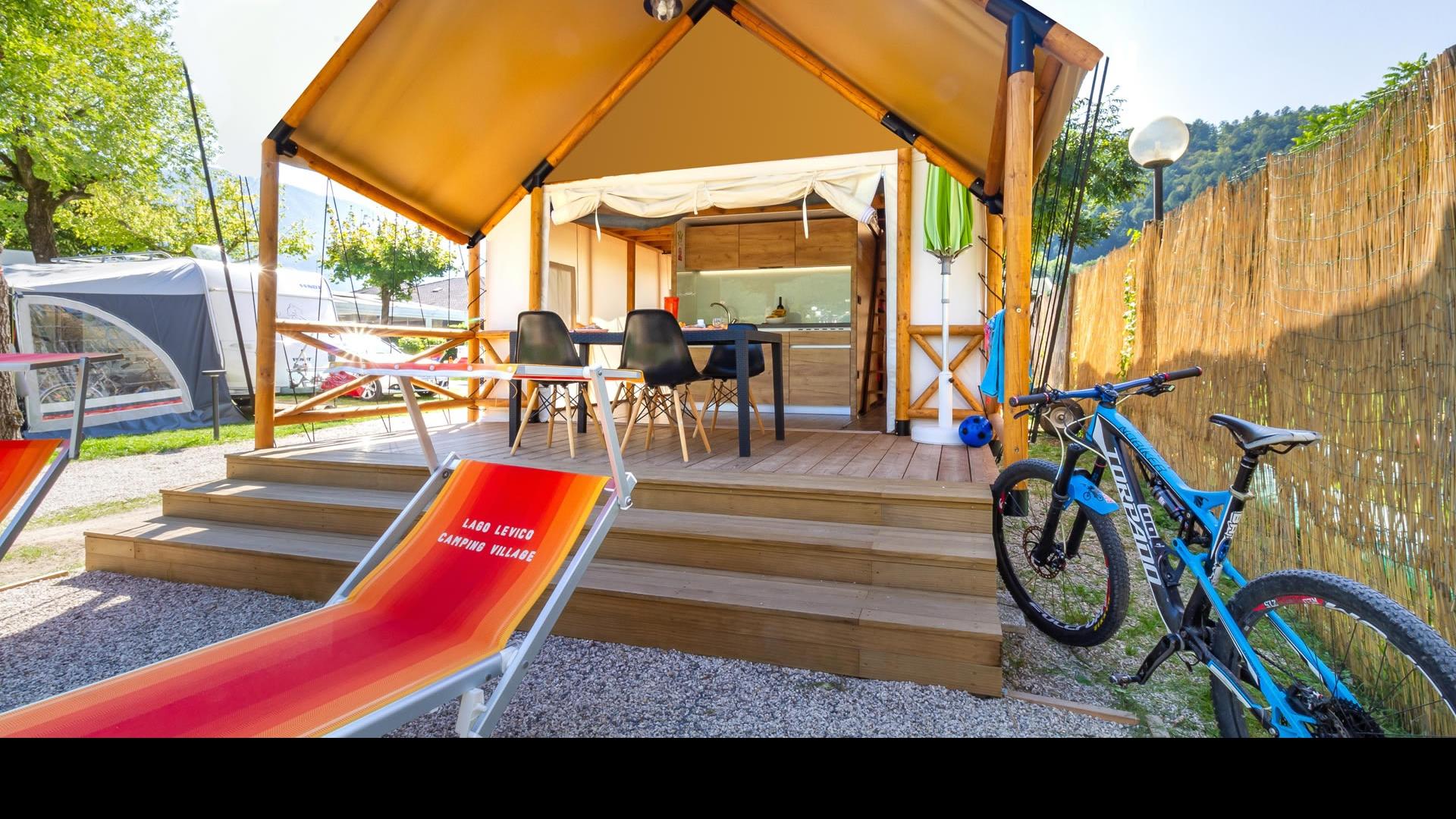 Glamping-Zelt mit Veranda, Fahrrad und Liegestühlen im Lago Levico Camping Village.